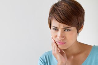 woman holding jaw from tooth pain before an extraction