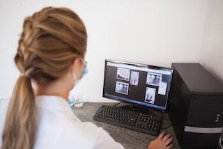 Dentist looking at x-rays on computer screen